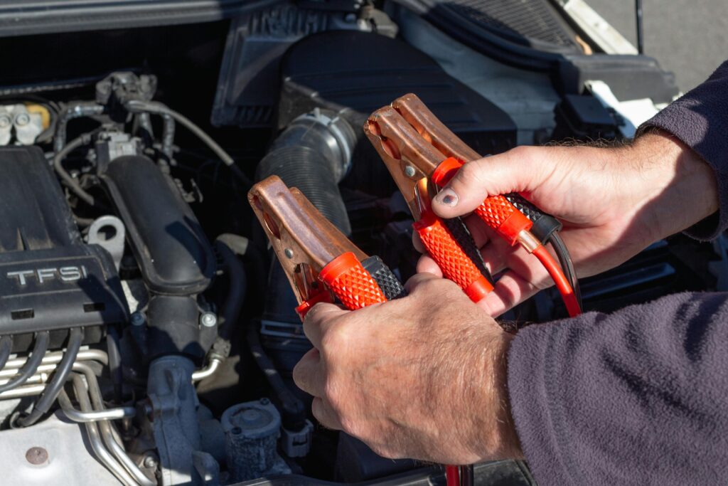 Man Holding Clips in Front of a Car Engine 